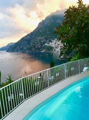 Une piscine avec vue sur une ville côtière et les montagnes.