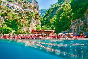 A coastal resort with a poolside area, beach umbrellas, and a building with a sign. - VILLA ROMANCE IN POSITANO (Positano)