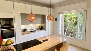 Una cocina moderna con armarios blancos, una isla central e iluminación colgante.