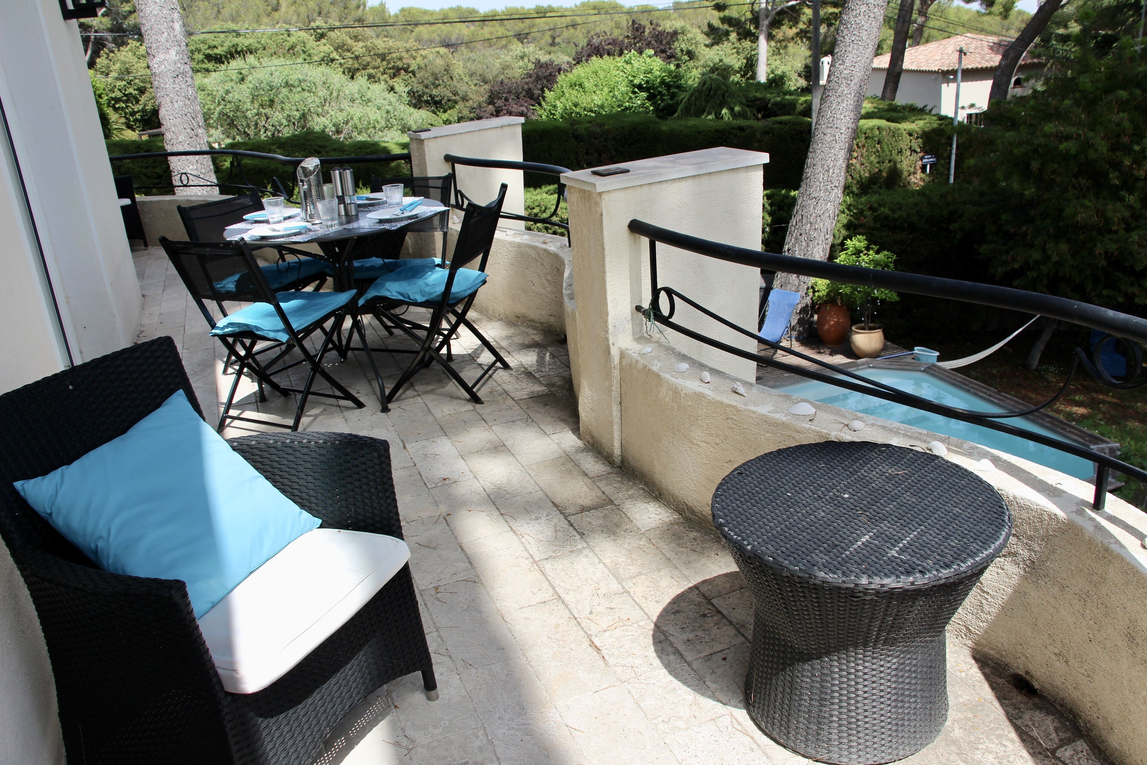A balcony with a table set for two, chairs, a small round table, and a potted plant.