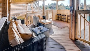 A covered outdoor seating area with wicker furniture and a view of the surrounding landscape. - Semi-Oceanfront Dog Friendly Home in Avon w/ Pool, Hot Tub, Tiki Bar, Game Room (Avon)