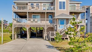 A two-story house with a balcony, a front door, and a garage. - Semi-Oceanfront Dog Friendly Home in Avon w/ Pool, Hot Tub, Tiki Bar, Game Room (Avon)