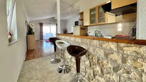 A kitchen with a stone backsplash, wooden cabinets, and a bar area with stools.