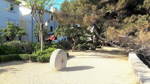 A courtyard with a gravel path, a large stone, and trees.