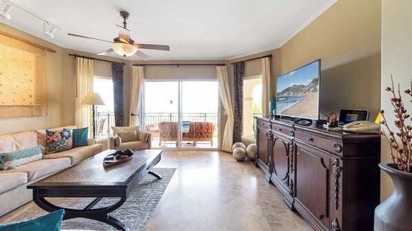 A spacious living room with a sofa, coffee table, and a television on a cabinet.