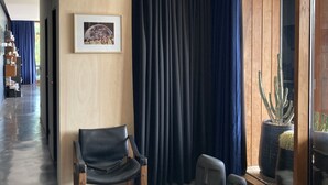 A modern living room with a large window, a black leather chair, a sofa, and a cactus plant.