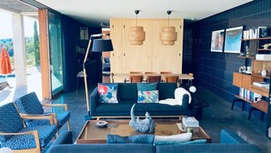 A modern living room with a dark blue sofa, a wooden coffee table, and a bookshelf.