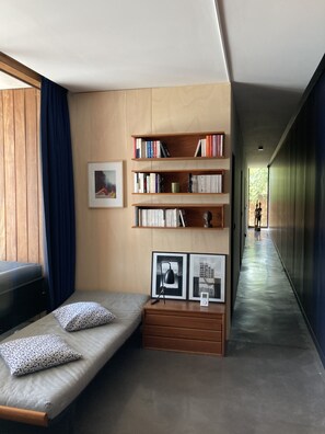 A modern room with a built-in bookshelf, a small sofa with patterned cushions, and framed pictures on the wall.