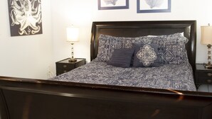 A bedroom with a dark wooden bed, patterned bedding, and two framed wall art pieces above the bed. - Ft Walton cozy condo w/ on-site pool. Near beaches (Fort Walton Beach)
