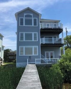 A two-story building with a wooden walkway leading to the entrance. - Kitty Hawk Bay Vista (Kill Devil Hills)