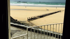 Blick auf einen Strand durch ein Fenster mit Metallgitter.