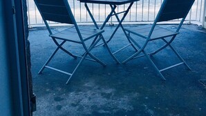 Ein Balkon mit zwei Stühlen und einem Tisch mit Blick auf einen Strand.