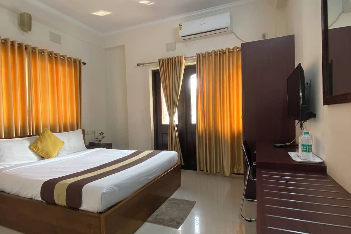Een hotelkamer met een bed, bureau, stoel, plafondventilator en een airconditioning.