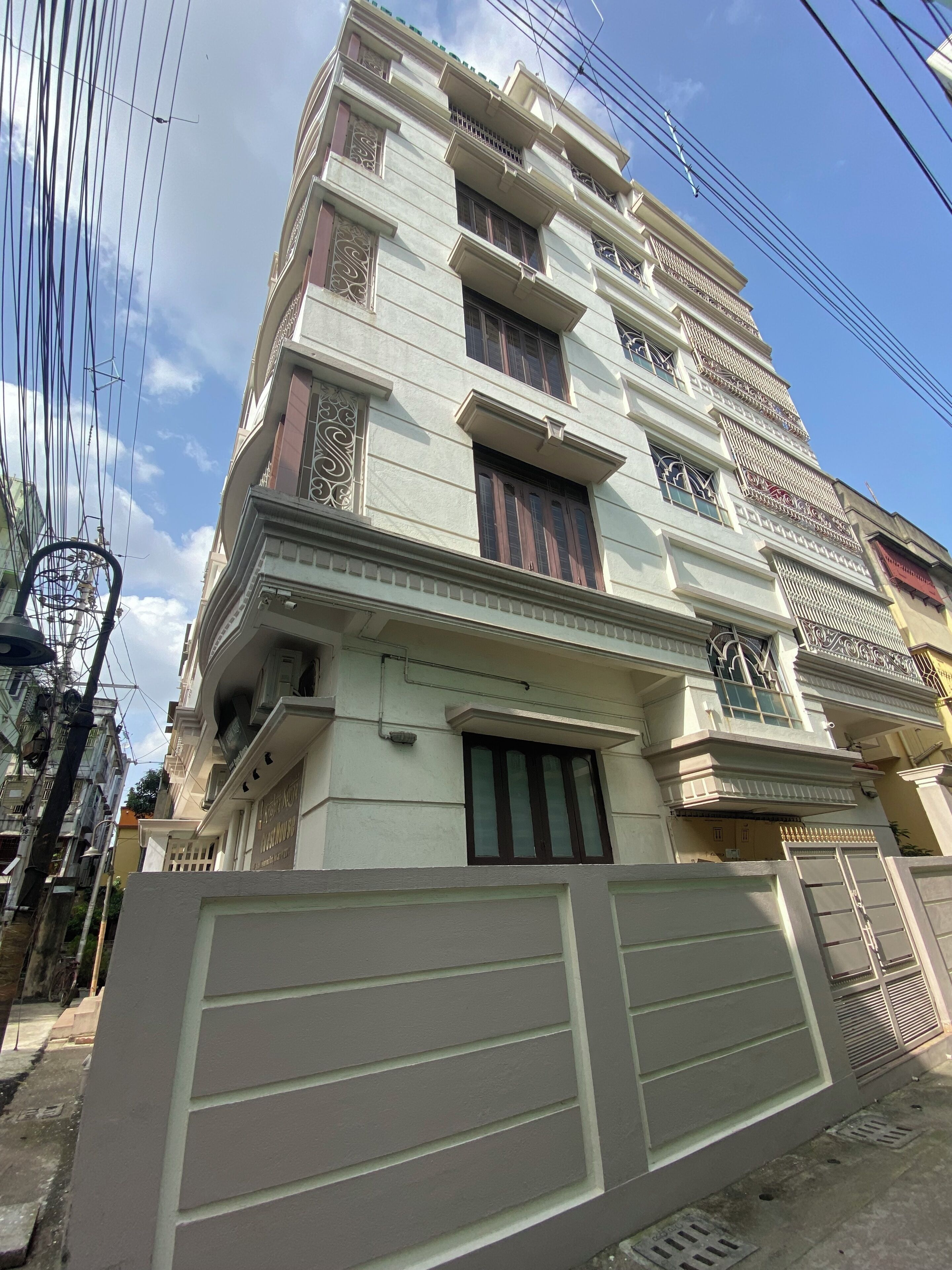 Um edifício residencial de vários andares com fachada simétrica, grandes janelas e grades decorativas.