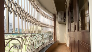 Een gang met een decoratieve balustrade, houten vloer en uitzicht op gebouwen.