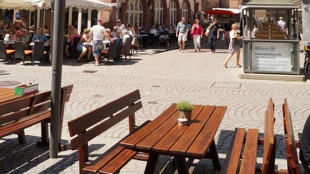 A historic square with traditional architecture, outdoor seating, and a prominent church tower.