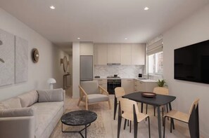 Uma cozinha moderna com armários brancos, uma sala de jantar com mesa e cadeiras, e uma sala de estar com sofá e mesa de centro.