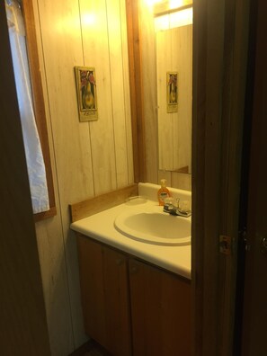 A bathroom with a wooden vanity, a sink, and a mirror. - Creekside Cabins - Mountain Laurel (Bryson City)