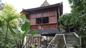 Un bâtiment traditionnel en bois, doté d’un toit en tuiles, d’un escalier menant à l’entrée et d’une enseigne indiquant « Café ».