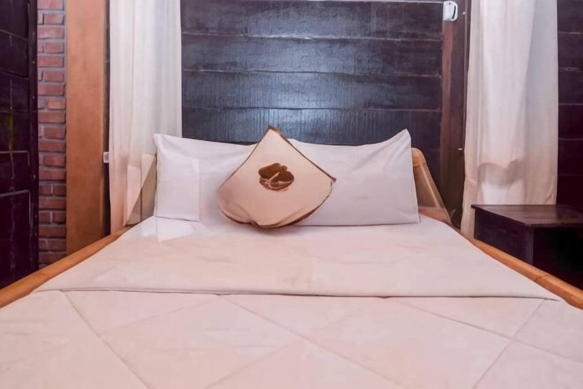 Een bed met hoofdbord, kussens en een houten frame.