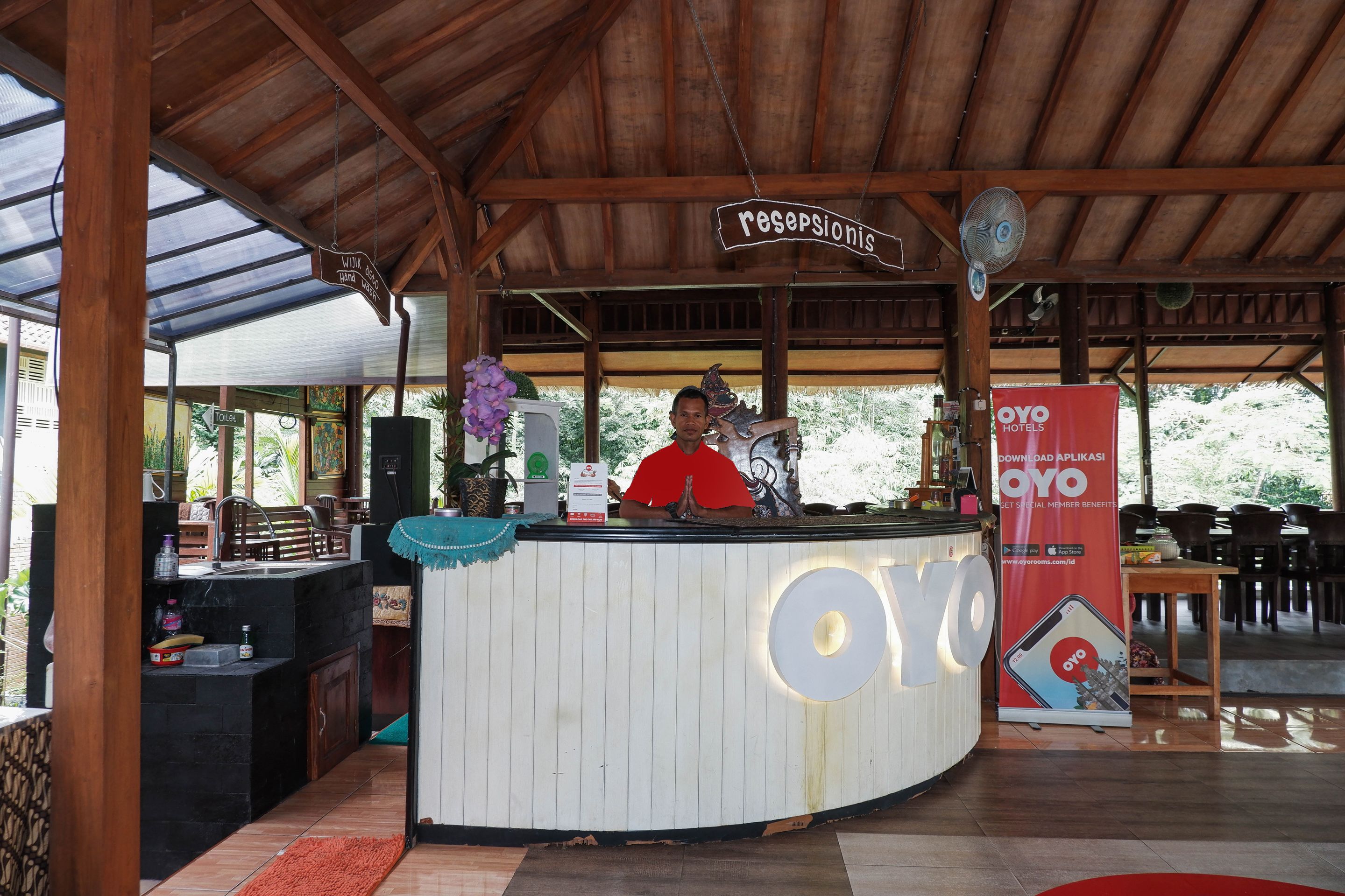 Ein Empfangsbereich mit Holzbalkendecke, einer Rezeption mit dem Schild 'receptionis' und einem roten Banner für OYO Hotels.