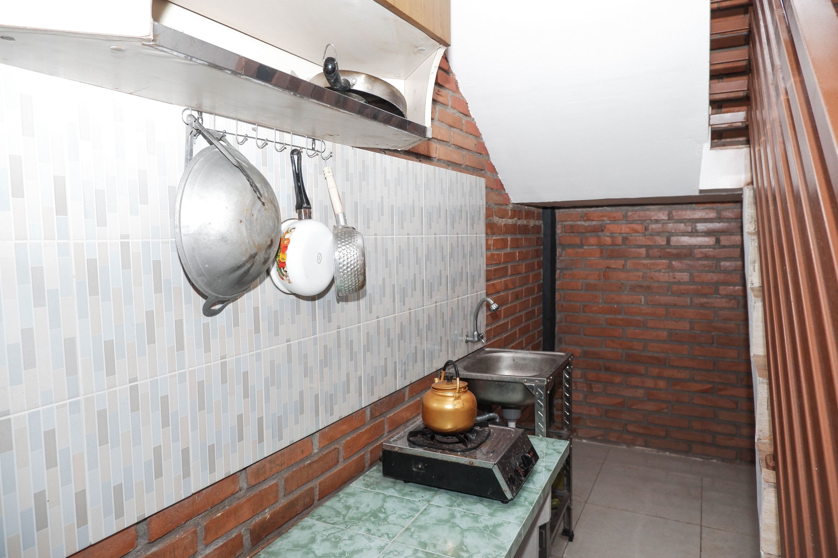 A kitchen with a gas stove, hanging pots, and a tiled backsplash.