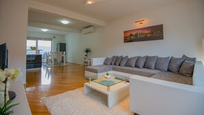 A modern living room with a sofa, a glass coffee table, and a cityscape painting on the wall. - Villa Tea in Imotski, private pool (Zmijavci)