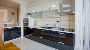 A modern kitchen with black and white cabinetry, a stainless steel sink, and a built-in oven. - Villa Tea in Imotski, private pool (Zmijavci)