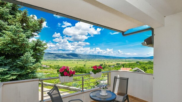 A balcony with a view of a green landscape, a chair, a small table, and potted plants. - Villa Tea in Imotski, private pool (Zmijavci)