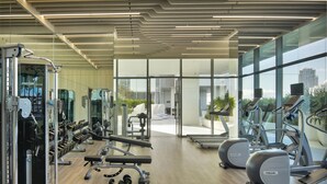 Een moderne sportschool met diverse fitnessapparaten, grote ramen en uitzicht op de stad.