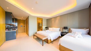 Een moderne hotelkamer met twee bedden, een bankje, een bureau en een badkamer.