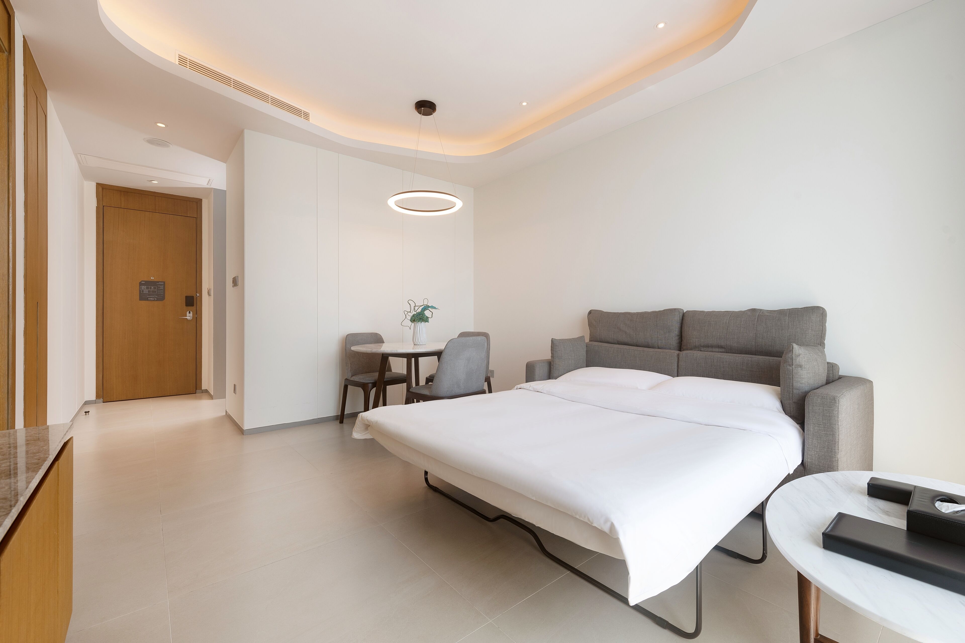 A modern hotel room with a large bed, a desk, and a chair.