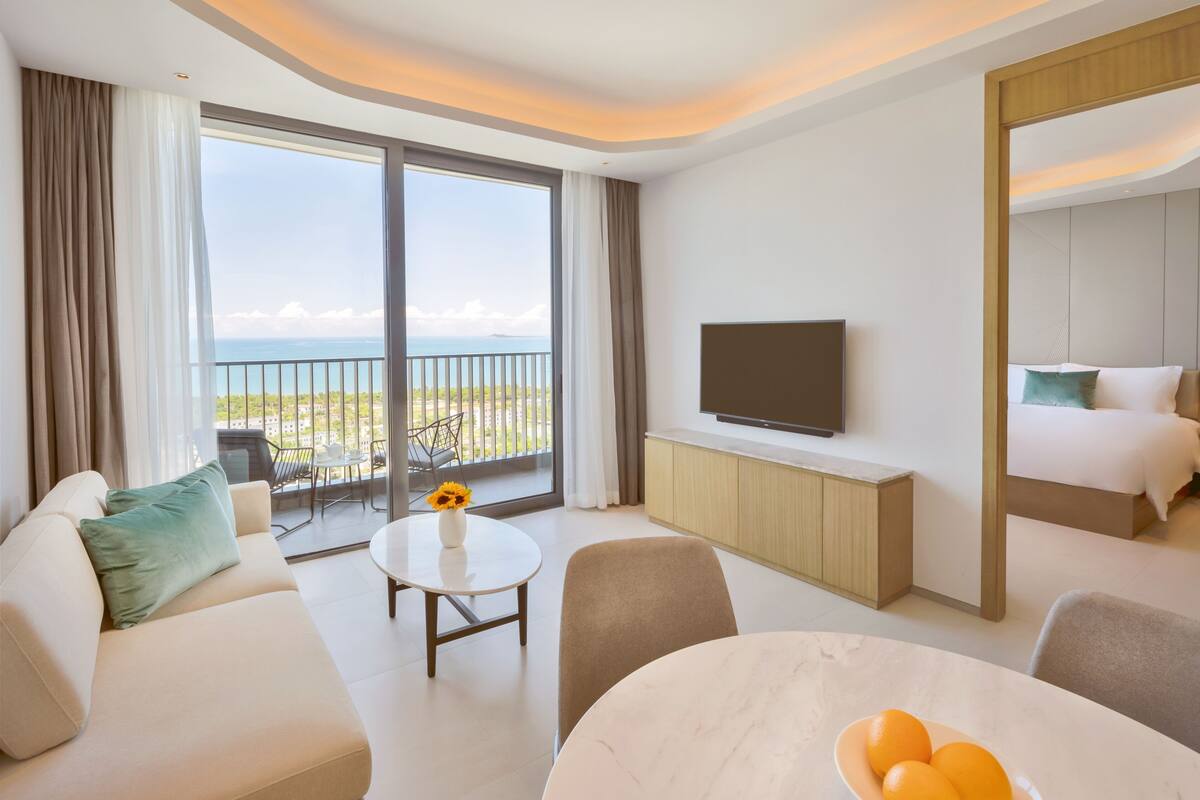 Une chambre d’hôtel moderne dotée d’un balcon, d’une télévision à écran plat, d’un lit, d’un coin repas et offrant une vue sur l’océan.