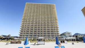 Een hoog hotel met meerdere balkons, een ligging aan het strand en een heldere lucht.