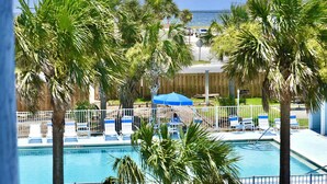 A pool area with palm trees, lounge chairs, and a view of the ocean. - Sundown B 34 (Pensacola)