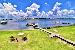 A waterfront property with a dock, grassy areas, and a clear view of the water.