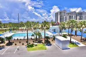 Un hotel con piscina, palmeras y aparcamiento.