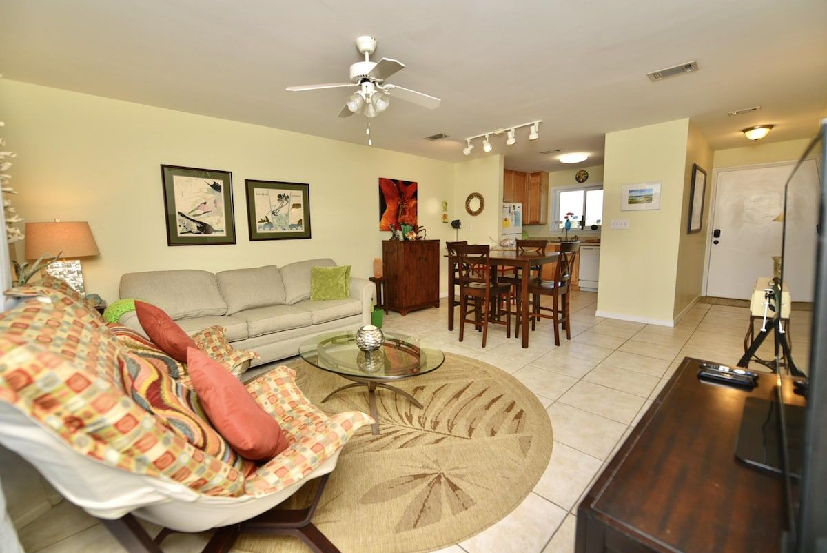 A living room with a sofa, coffee table, and a dining area with chairs and a table.