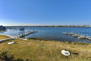 A waterfront property with a dock, grassy areas, and a clear view of the water.