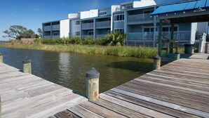 A waterfront property with a wooden dock, a building with multiple balconies, and a covered area. - Sundown B 34 (Pensacola)