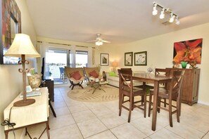 A dining area with a table and chairs, a ceiling fan, and a view through a glass door.