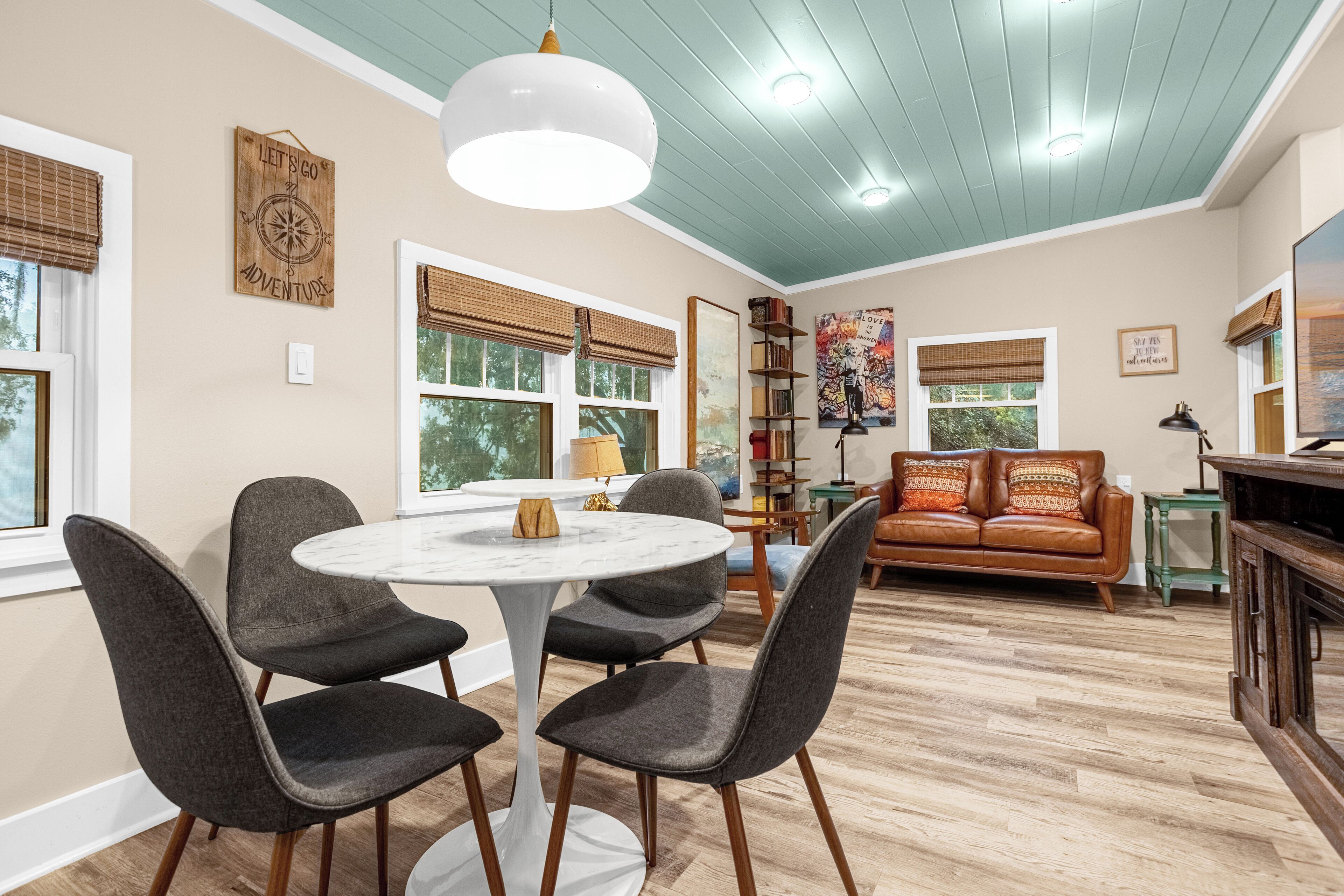 A dining area with a round table and four chairs, a sofa, and a bookshelf.
