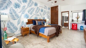 A bedroom with a bed, wooden headboard, nightstands, a ceiling fan, and a bathroom visible through an open door. - HGTV Villa for Couples, 4-Min Walk to the Scuba Pick-up Pier (Cozumel)