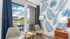 A room with a balcony, two chairs, a table with a book, a lamp, and a wooden nightstand. - HGTV Villa for Couples, 4-Min Walk to the Scuba Pick-up Pier (Cozumel)