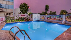 Piscina interior con borde de azulejos, rodeada de plantas en macetas y un mural.