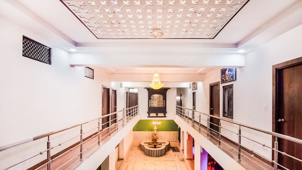 Pasillo de hotel de varios niveles con una araña central, un muro decorativo y una escalera.