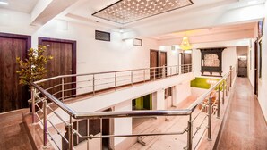 Un interior de varios niveles con una escalera central, barandillas de metal y un elegante candelabro.