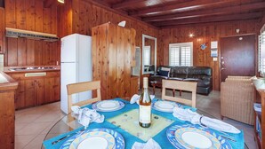A wooden cabin interior with a dining table set for two, a kitchen area, a living room with a sofa, and a door leading to another room. - Have fun at the beach in this one bedroom cozy 1 bedroom apartment. (San Diego)