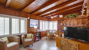 A wooden-paneled room with wicker furniture, a television, and a dining area. - Have fun at the beach in this one bedroom cozy 1 bedroom apartment. (San Diego)