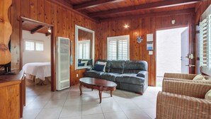 A wooden-furnished living room with a sofa, a coffee table, and a wicker chair. - Have fun at the beach in this one bedroom cozy 1 bedroom apartment. (San Diego)